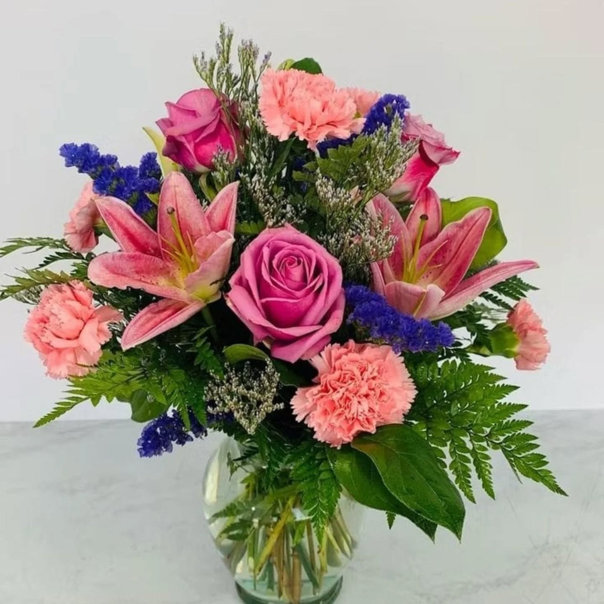 Glass vase flower arrangement with pink oriental lilies, pastel roses, and carnations – Flower On Wheels same-day delivery